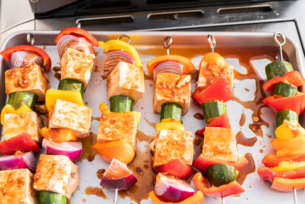 Fertig bestückte Tofu-Spieße mit buntem Paprika, Zucchini und Zwiebel auf einem Blech