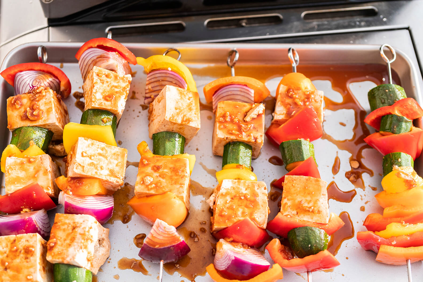 Fertig bestückte Tofu-Spieße mit buntem Paprika, Zucchini und Zwiebel auf einem Blech