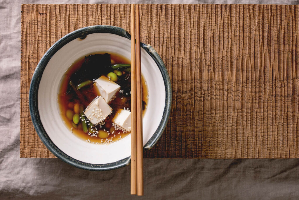 Tofu-Miso-Suppe mit Wakame, grünen Bohnen und Edamame in dunkler Schale