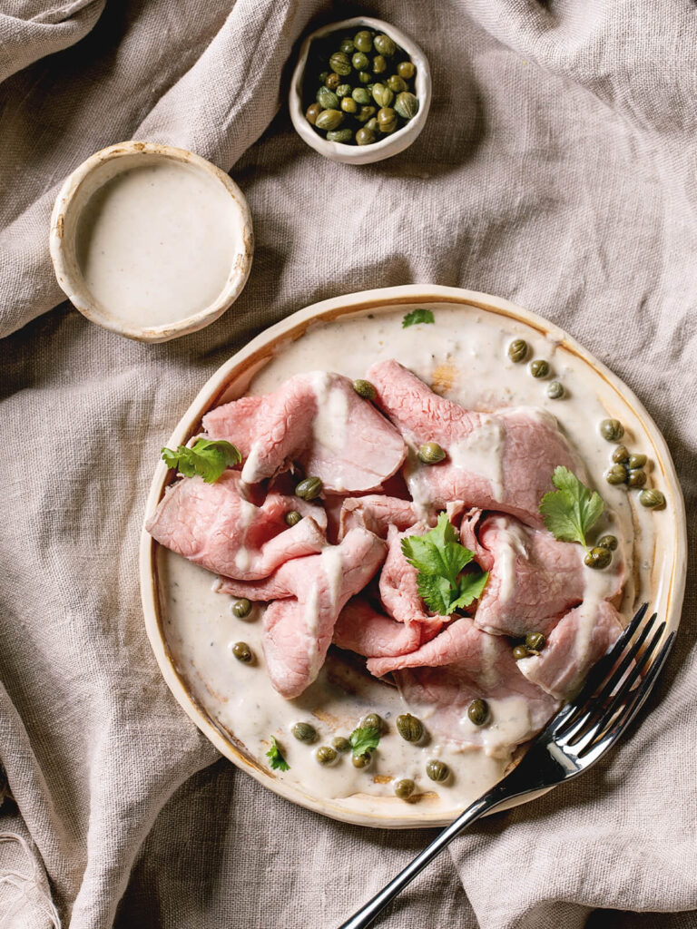 Komponenten für Vitello Tonnato – Kalbfleischscheiben, Schälchen mit Thunfisch-Soße und Kapern