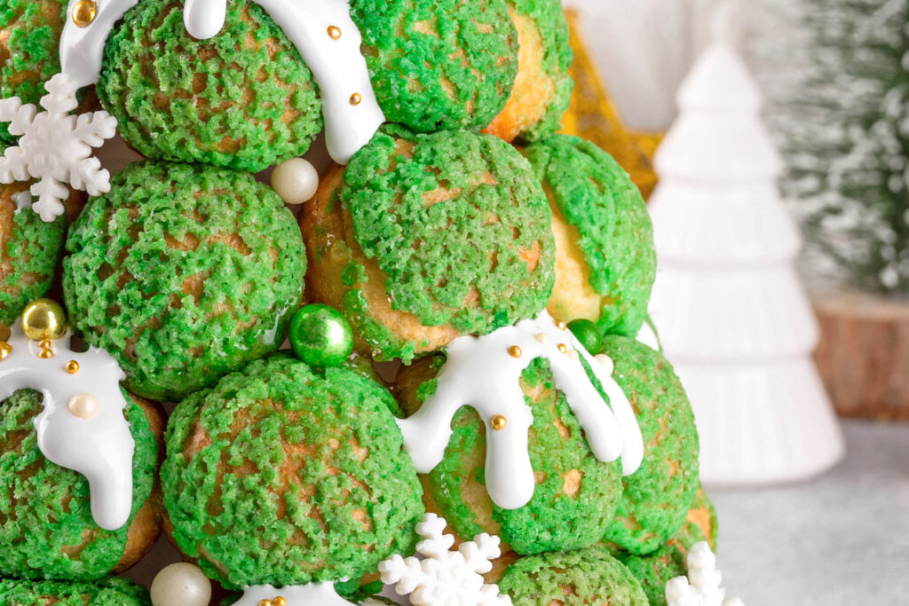 Weihnachts-Croquembouche aus grünen Craquelin-Windbeuteln mit weißem Zuckerguss und goldenen Zuckerperlen