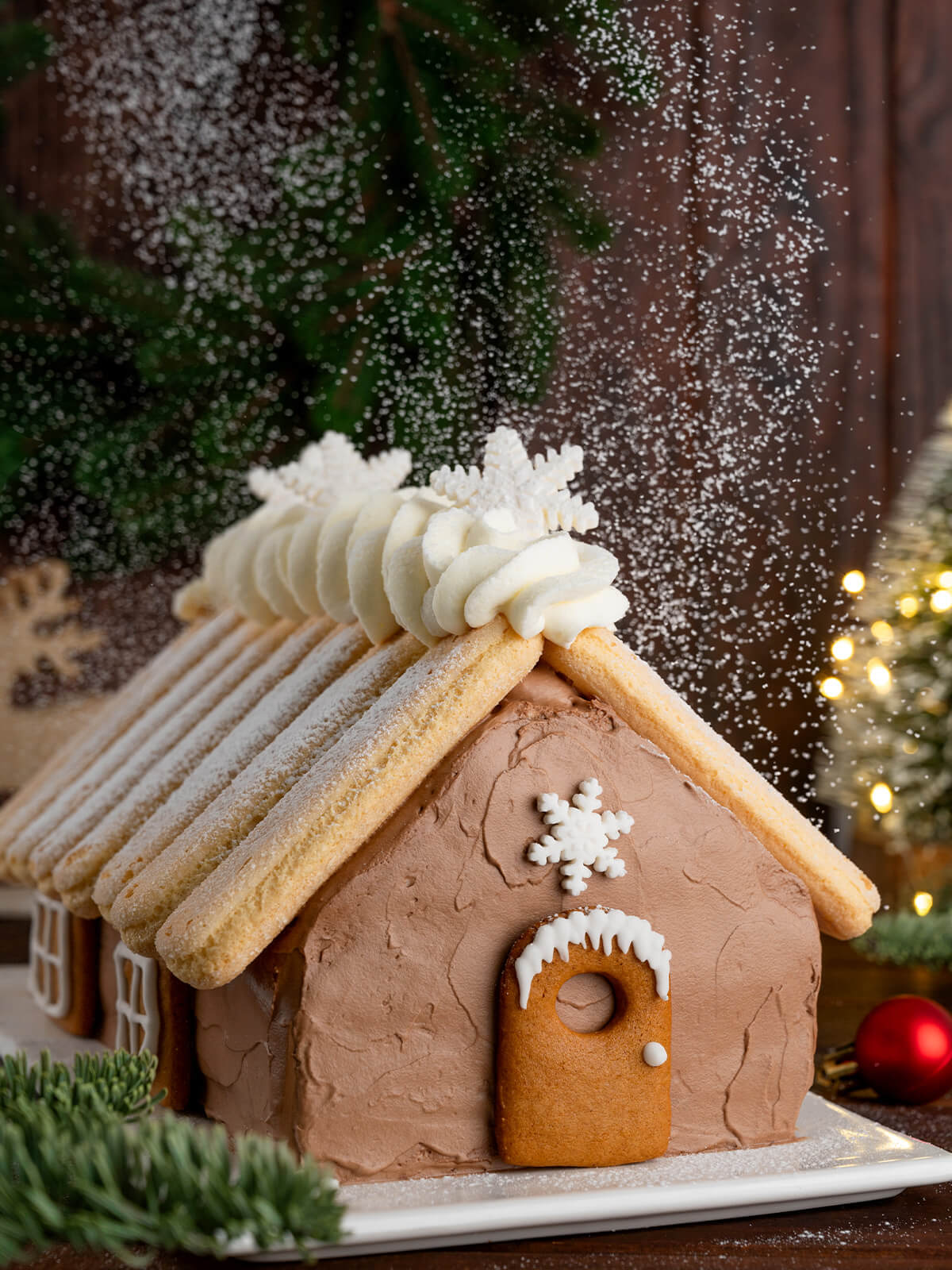 Weihnachts-Schoko-Hauskuchen mit Löffelbiskuit-Dach, Sahnefirst und herabrieselndem Puderzucker