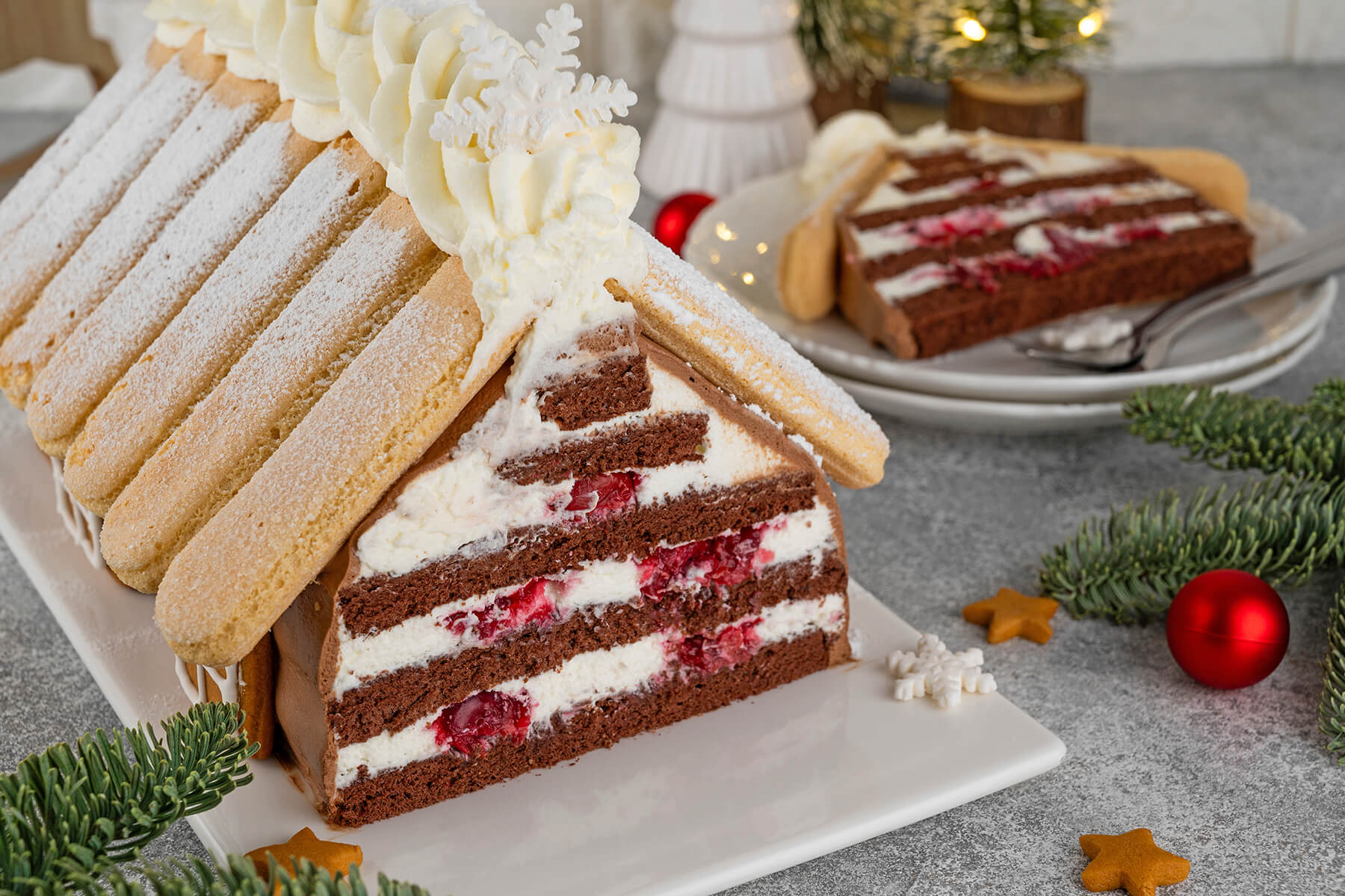 Angeschnittener Weihnachts-Schoko-Hauskuchen mit Sahne-Kirsch-Schichten und Löffelbiskuit-Dach