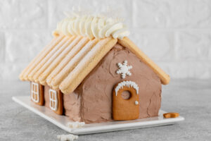 Schoko-Hauskuchen mit Löffelbiskuit-Dach und Lebkuchen-Fenstern an der Seitenwand