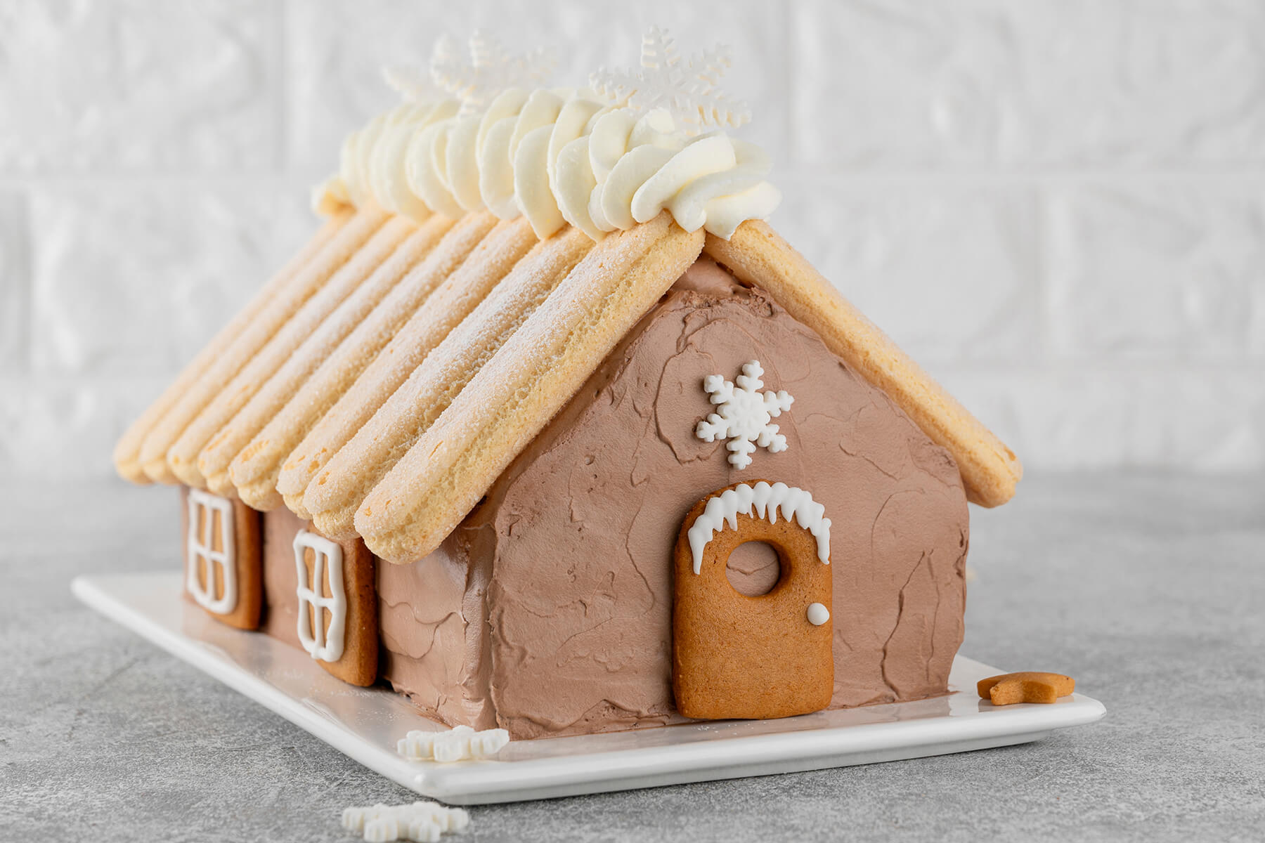 Schoko-Hauskuchen mit Löffelbiskuit-Dach und Lebkuchen-Fenstern an der Seitenwand
