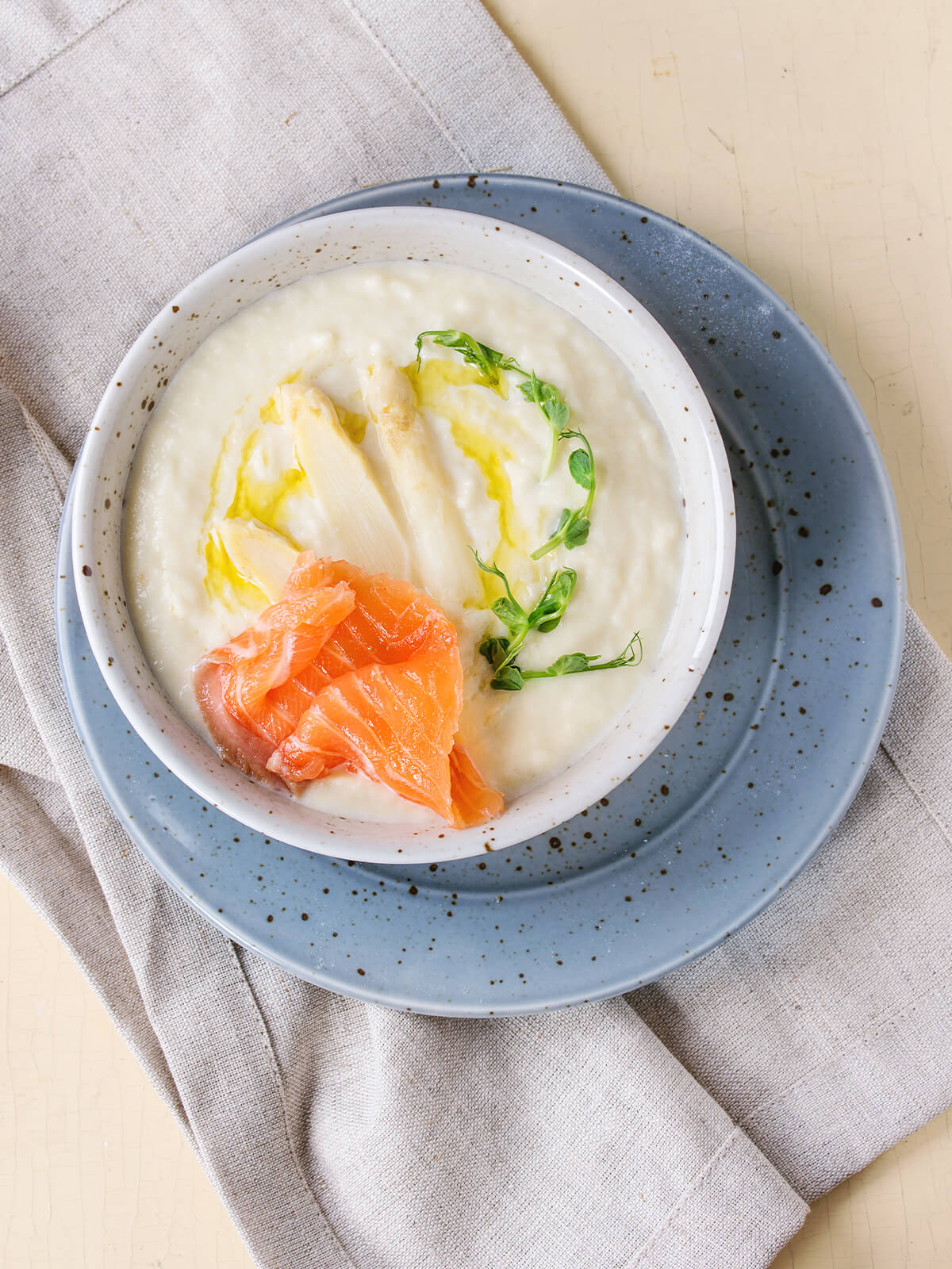 Weiße Spargel-Cremesuppe mit Streifen von Räucherlachs, Spargelspitzen und Erbsensprossen