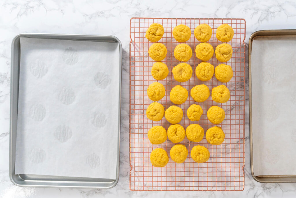 Frisch gebackene, sonnengelbe Zitronen-Cookies kühlen auf einem Kuchengitter zwischen zwei Backblechen aus