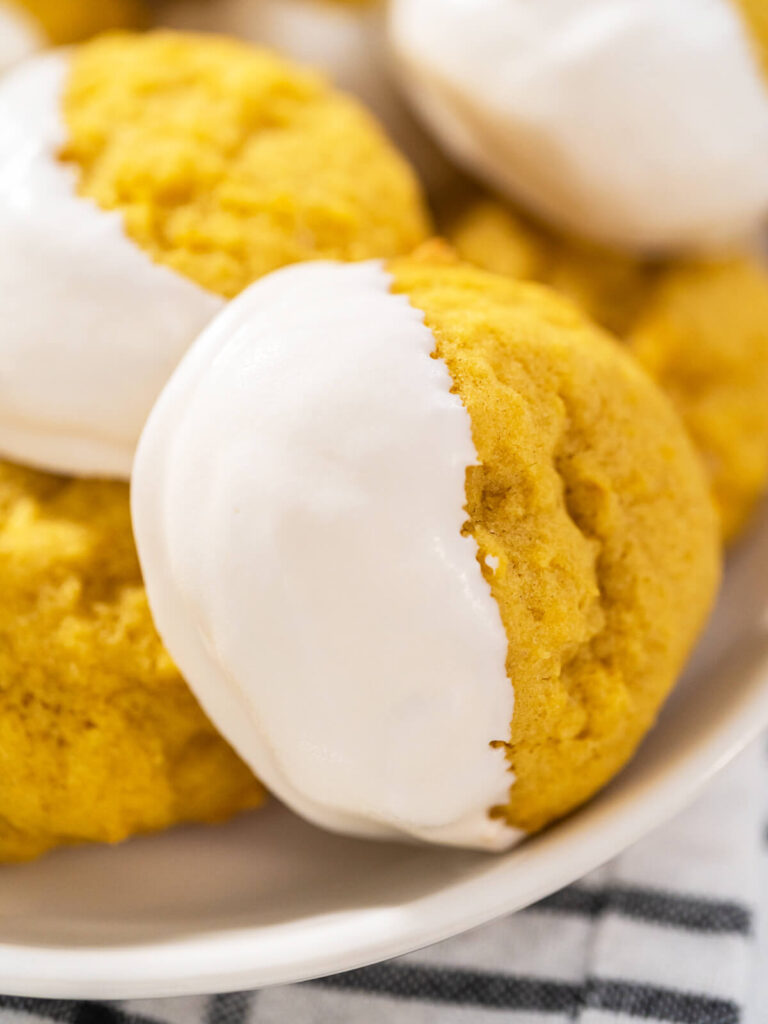 Weiche Zitronen-Cookies halb in weißer Schokolade getaucht auf hellem Untergrund