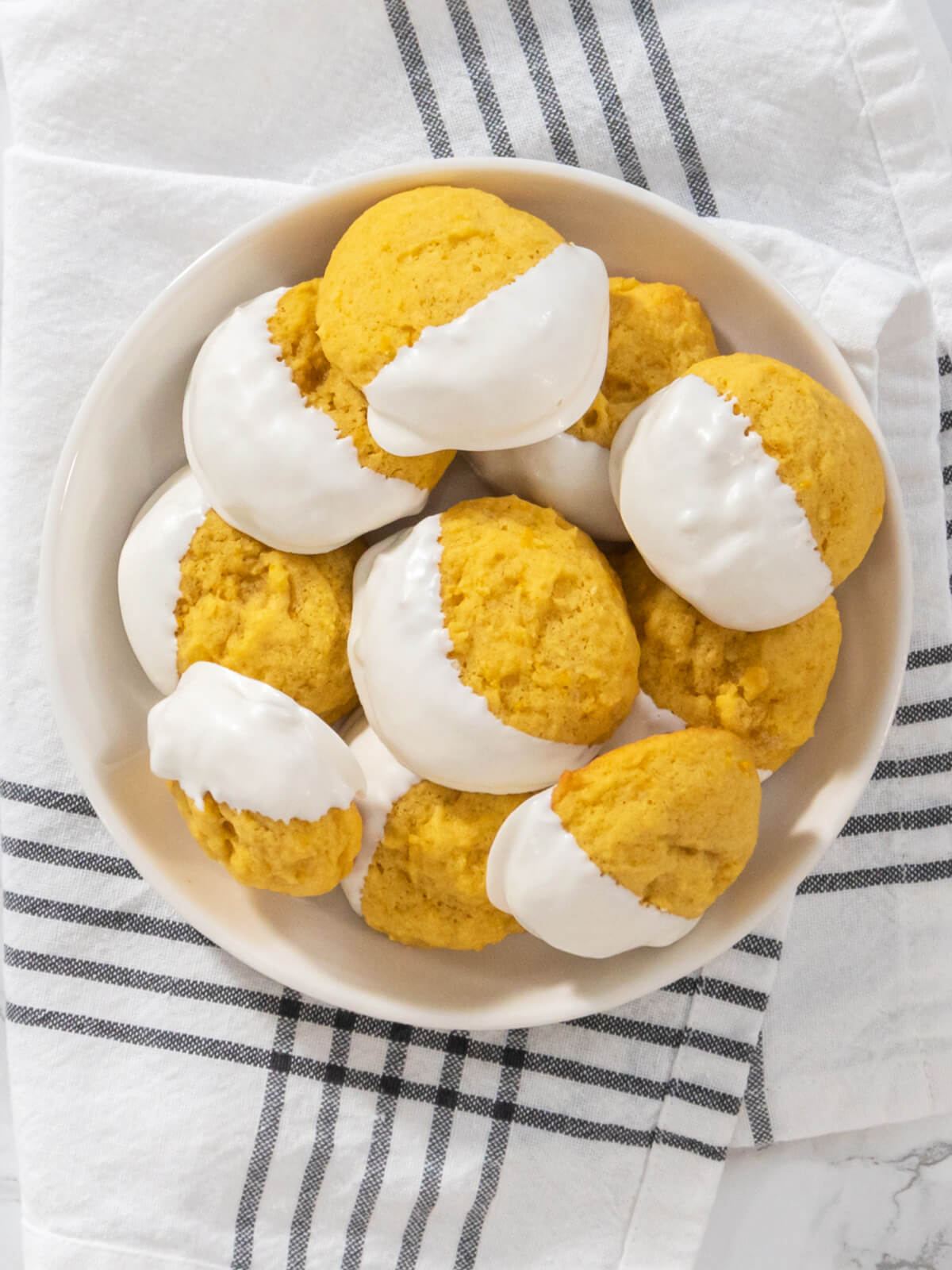 Weiche Zitronen-Cookies zur Hälfte in weiße Schokolade getaucht auf hellem Untergrund