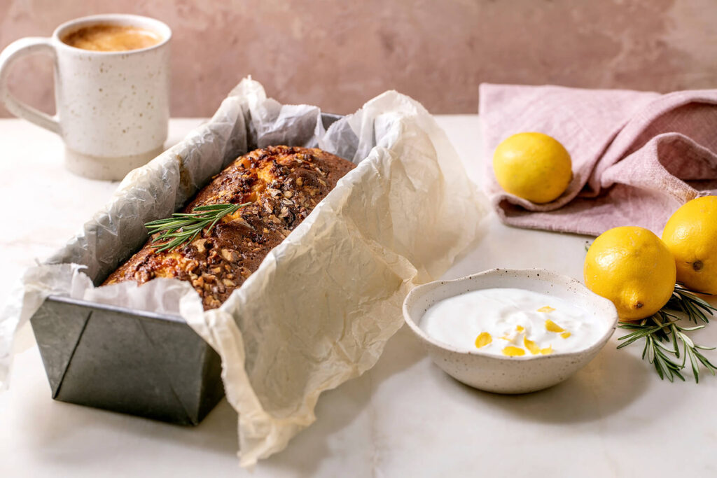 Zitronen-Pound-Cake mit Rosmarin, Walnüssen und Rosinen in der Kastenform mit Zitronenscheiben