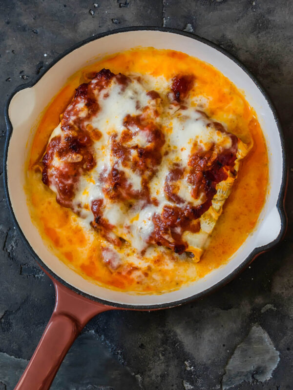 Goldbraun überbackene Zucchini-Cannelloni mit geschmolzenem Mozzarella und Tomatensauce in der Pfanne