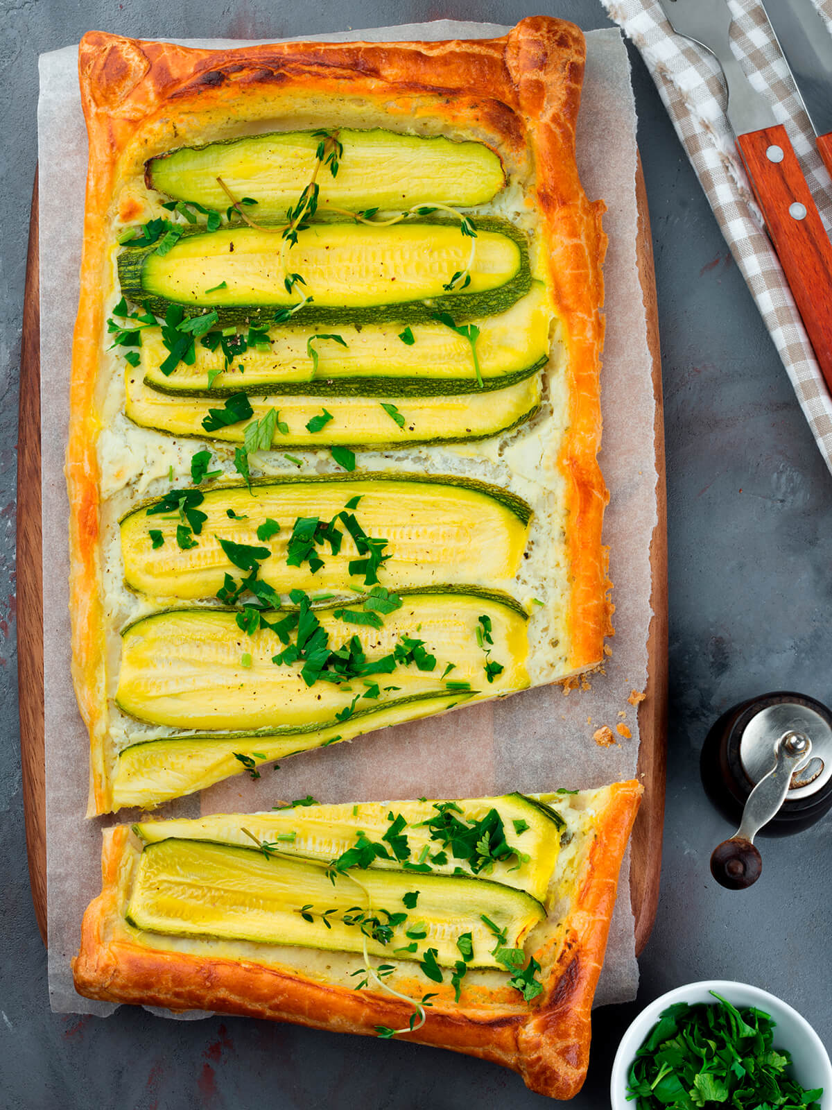 Angeschnittene Zucchini-Ricotta-Tarte aus Blätterteig mit Ricotta-Schicht und längs aufgelegten Zucchini