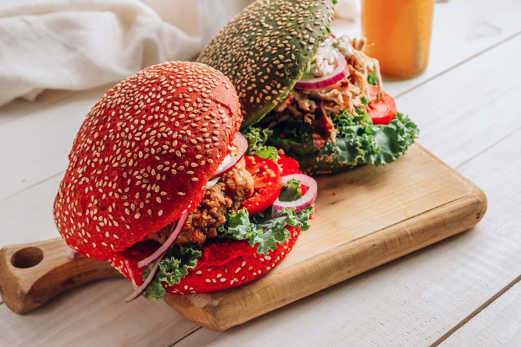 Nahaufnahme von rotem und grünem Hähnchen-Burger mit Grünkohl, Tomate und roter Zwiebel