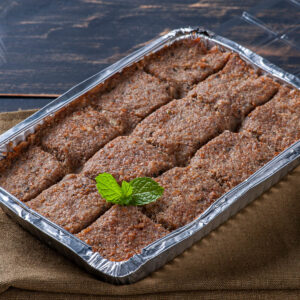 Gebackener Quibe de Forno in einer Form, in Rauten geschnitten, goldbraune Kruste und mit einem Zweig frischer Minze garniert