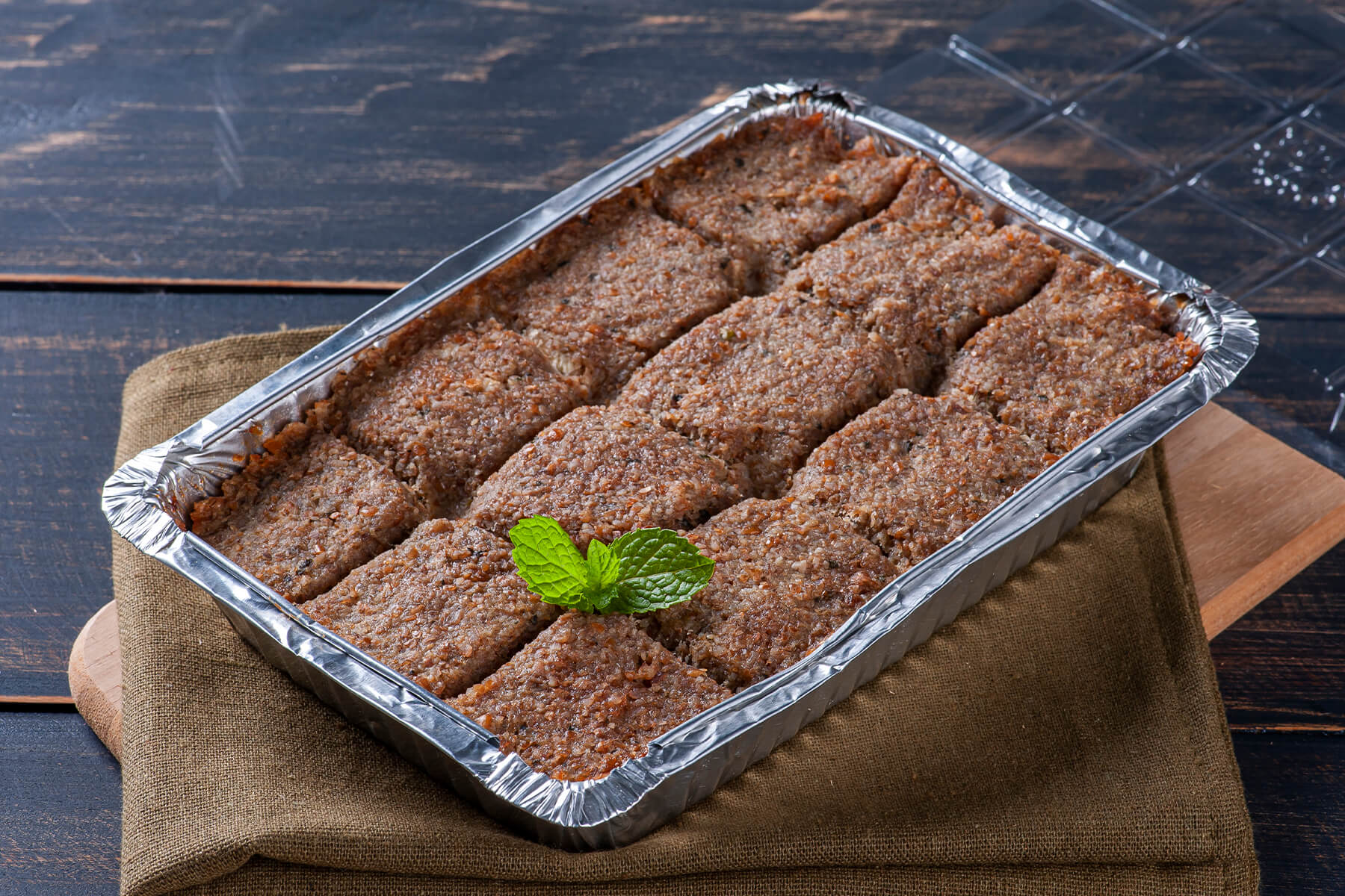 Frisch gebackener Quibe de Forno in einer rechteckigen Form, in Rauten geschnitten, mit goldbrauner Kruste und einem Zweig frischer Minze in der Mitte