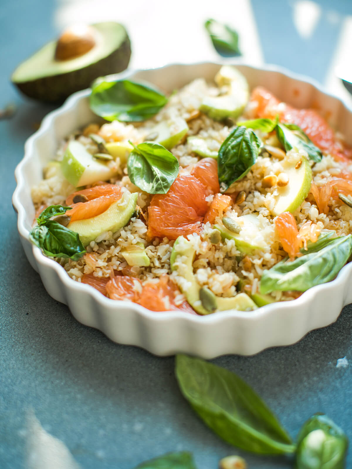 Reissalat mit rosa Grapefruit-Filets, grünen Apfelspalten, Avocadoscheiben, gerösteten Kürbiskernen und frischem Basilikum in einer weißen geriffelten Form