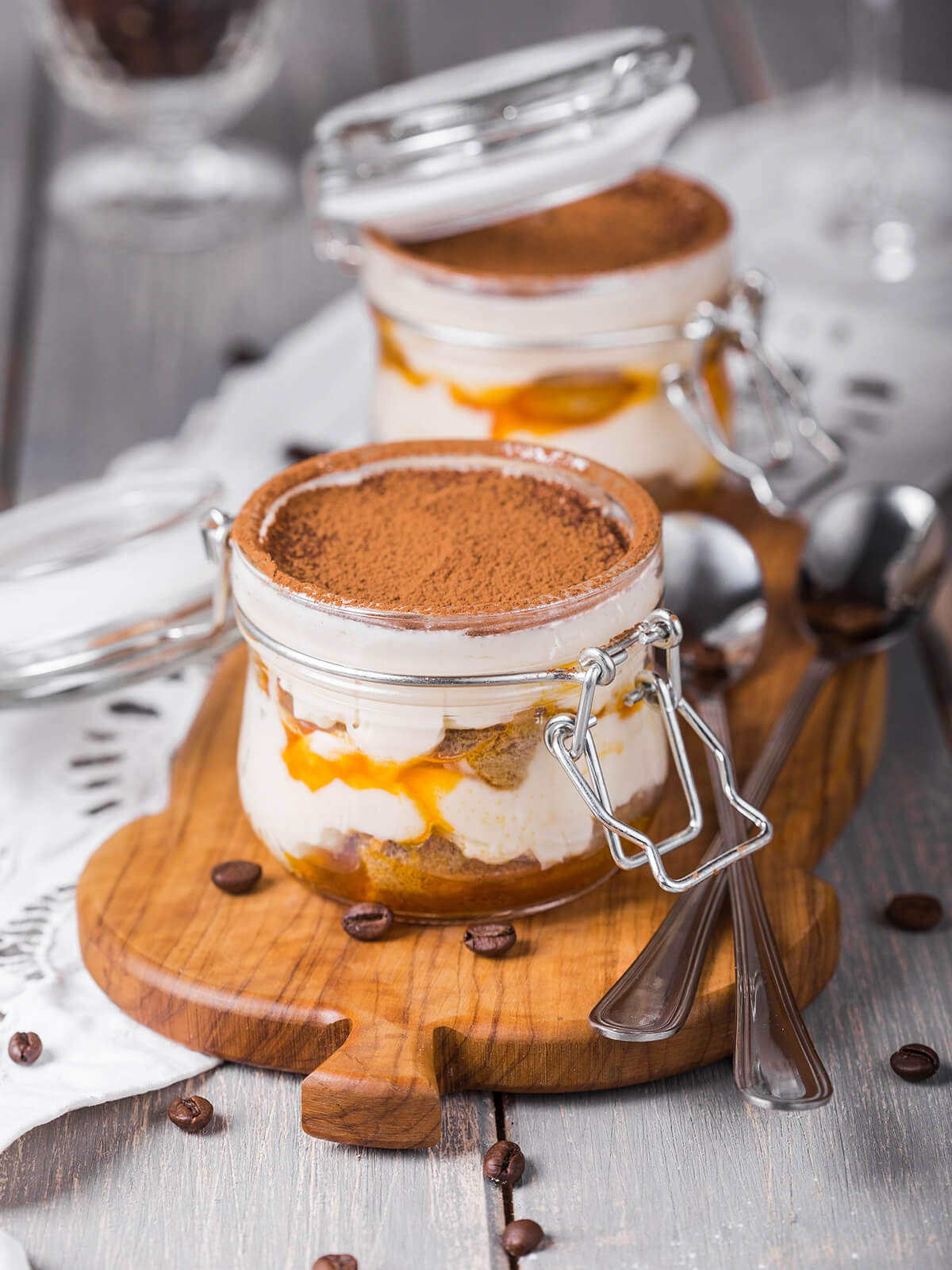 Sanddorn-Tiramisu im Bügelglas mit Kakao bestäubt, weißer Mascarpone-Creme, getränkten Löffelbiskuits und leuchtend orangem Sanddorn-Püree in sichtbaren Schichten