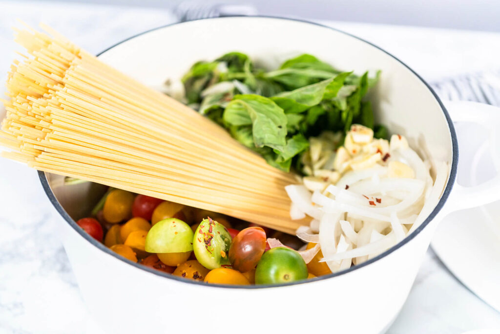 Vegetarische One-Pot-Pasta mit Spaghetti, bunten Kirschtomaten, geriebenem Hartkäse und frischem Basilikum