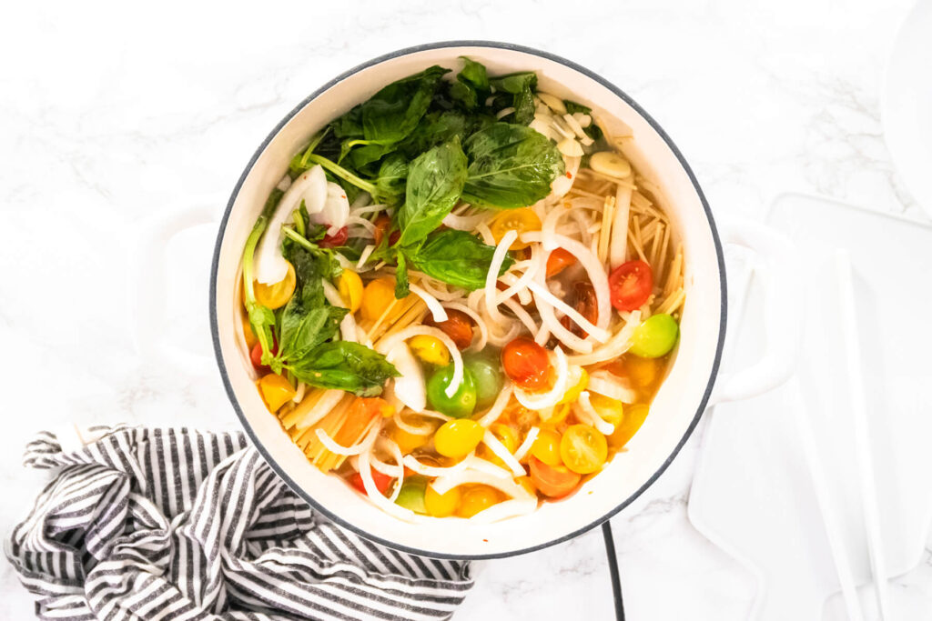 Vegetarische One-Pot-Pasta mit Spaghetti, bunten Kirschtomaten, geriebenem Hartkäse und frischem Basilikum