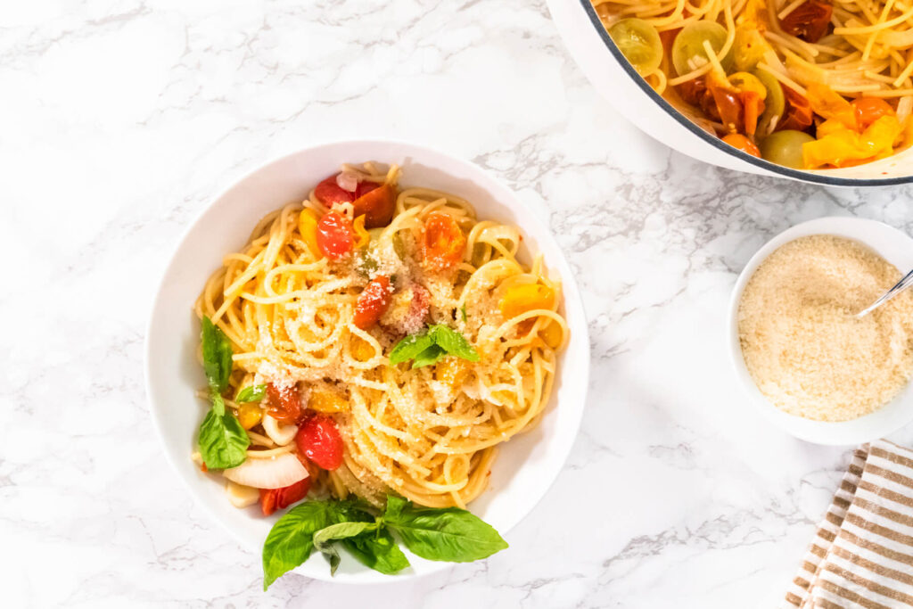 Vegetarische One-Pot-Pasta mit Spaghetti, bunten Kirschtomaten, geriebenem Hartkäse und frischem Basilikum
