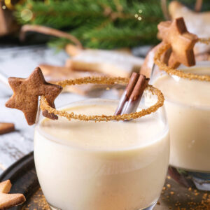 Cremiger Weihnachts-Eierpunsch im Glas mit Zimt-Zucker-Rand, Zimtstange und einem Zimtstern als Garnitur