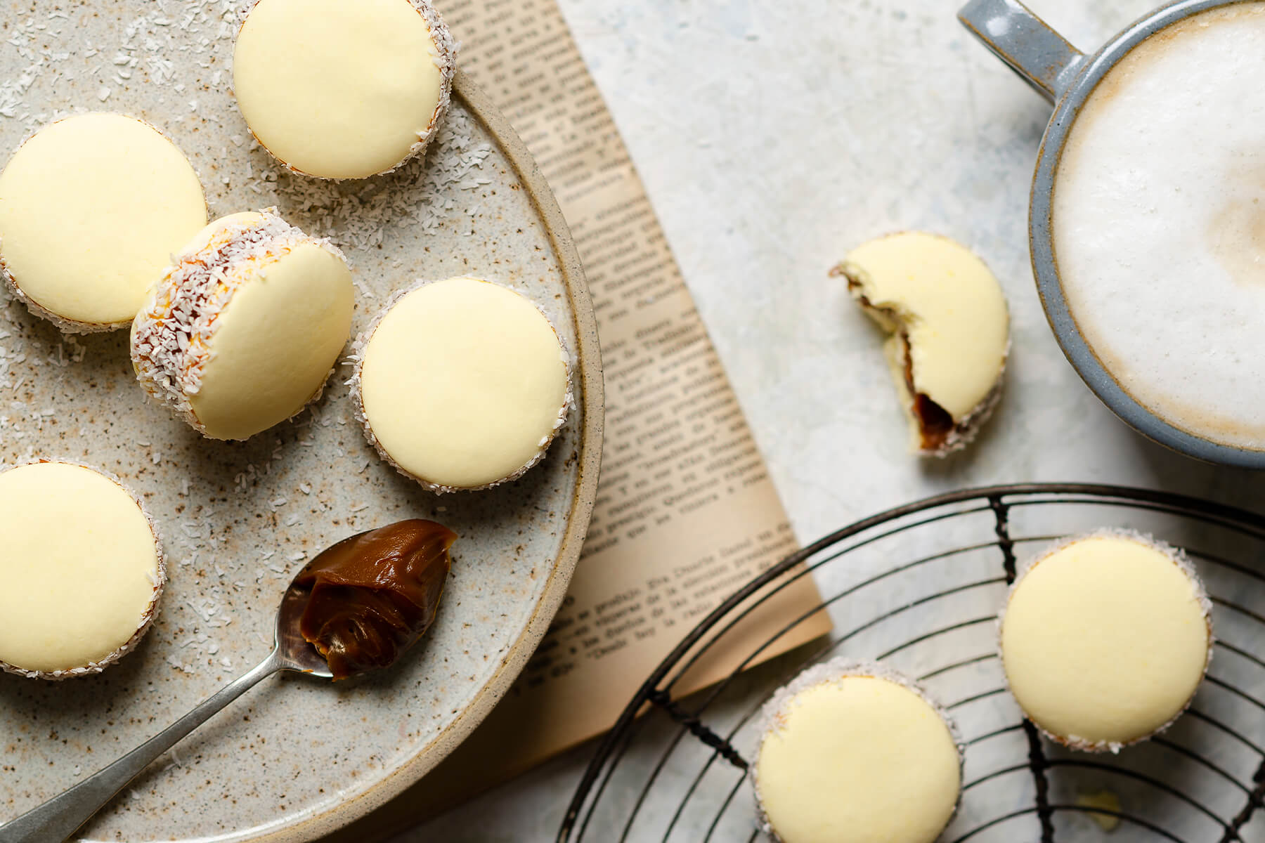 Alfajores de Maicena auf einem Teller neben einer Tasse Milchkaffee