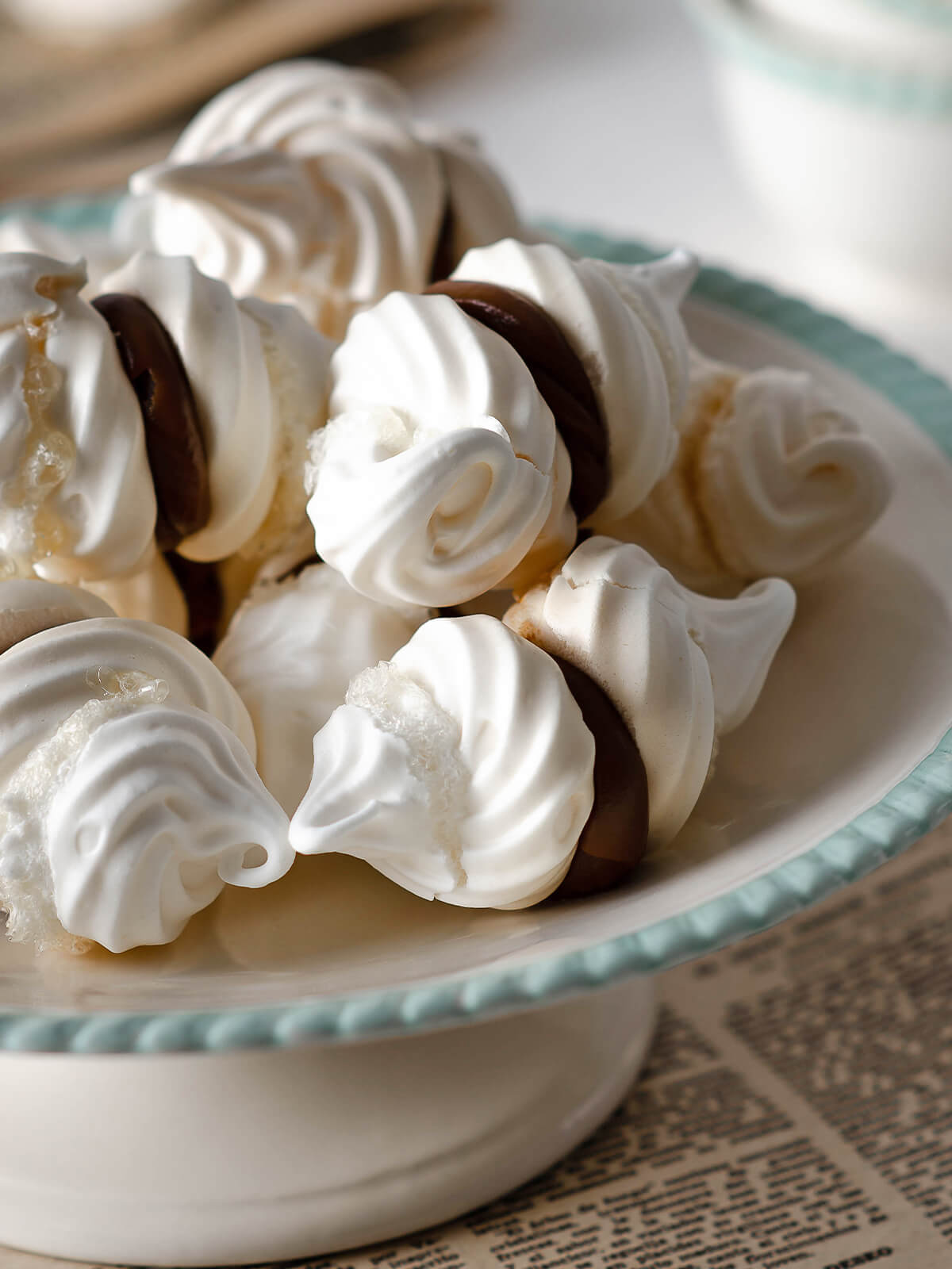 Weiße Baiser-Doppelkekse mit Dulce-de-Leche-Füllung in einer Schale mit mintgrünem Rand