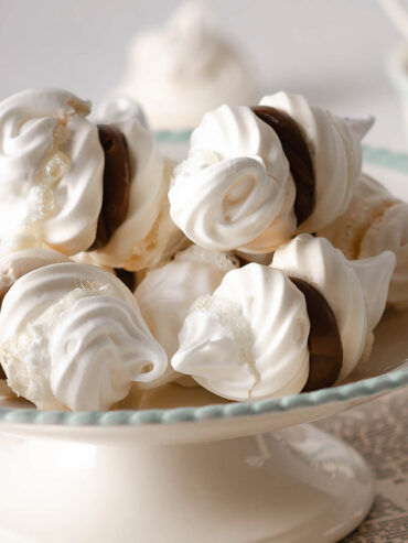 Nahaufnahme eines weißen Baiser-Doppelkekses mit sichtbarer Dulce-de-Leche-Füllung