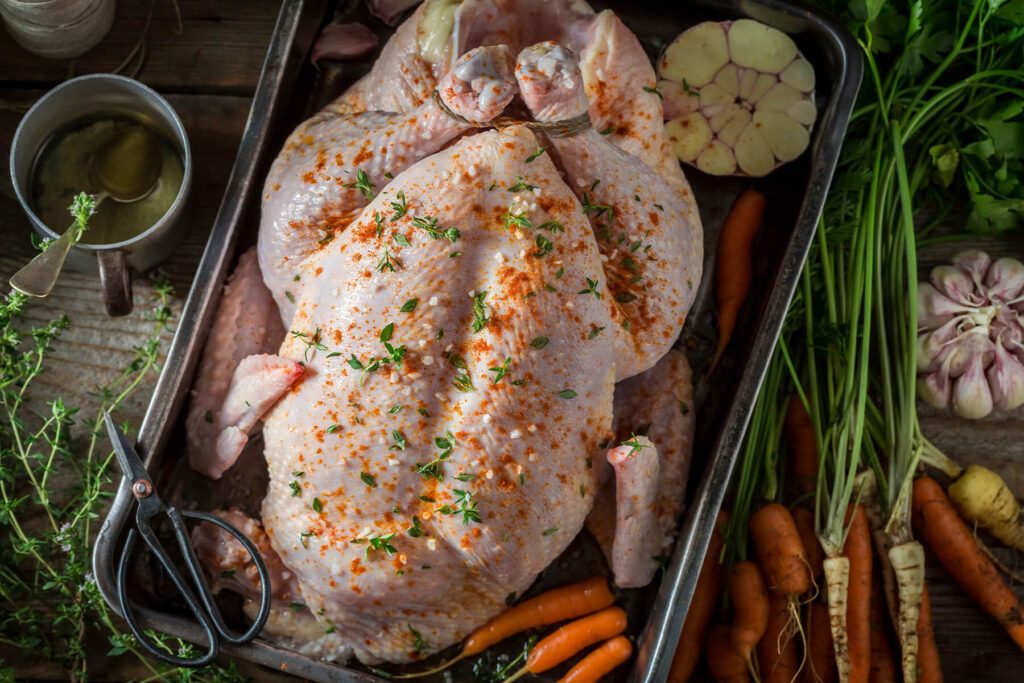 Rohes ganzes Hähnchen mit Salz, edelsüßem Paprika und Thymian, die Keulen mit Küchengarn zusammengebunden