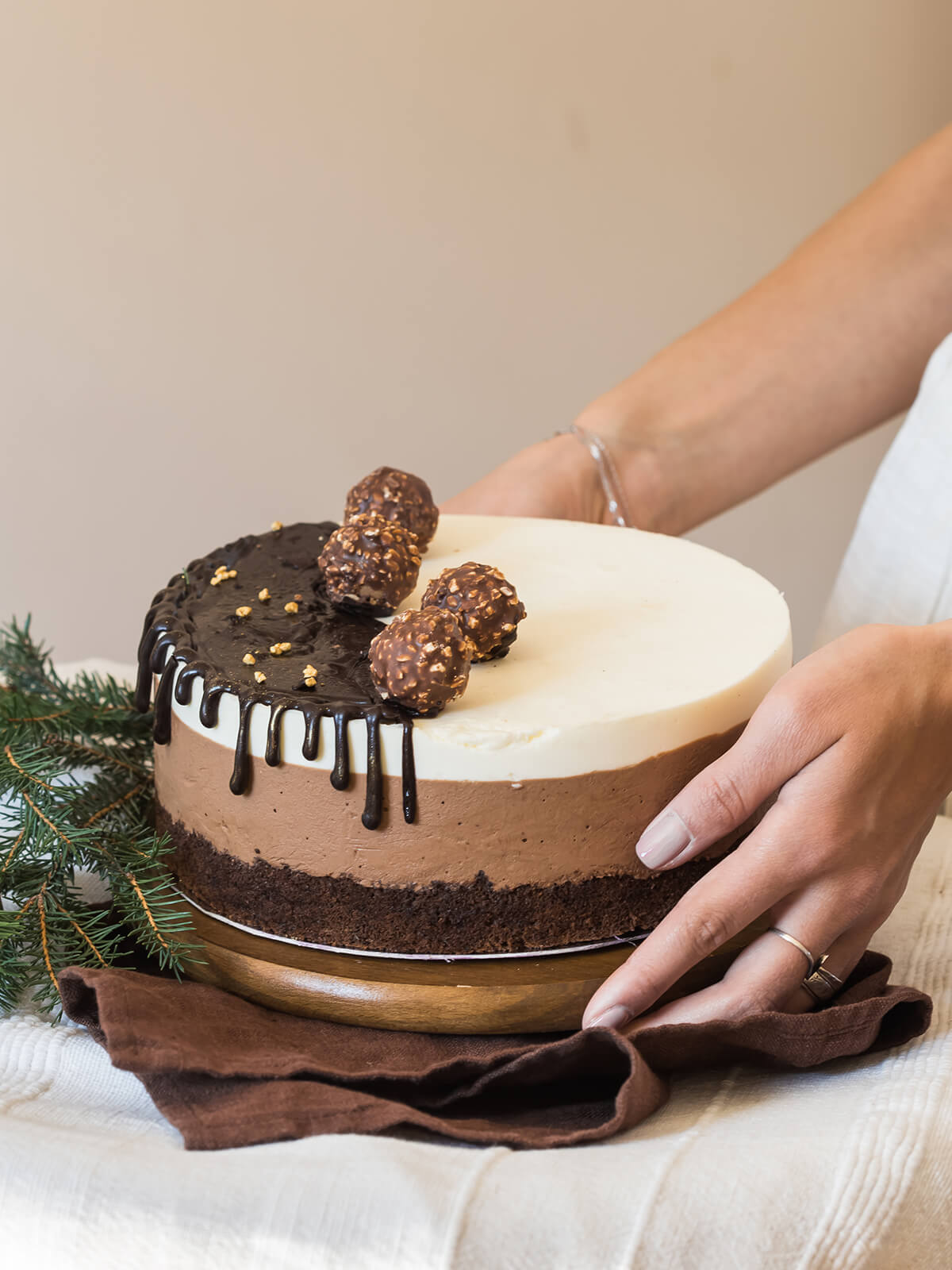 Ganze Schokoladen-Mousse-Torte mit Schokoladenguss und Schoko-Haselnuss-Kugeln wird mit beiden Händen gehalten