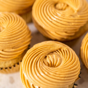 Karamellfarbene Dulce-de-Leche-Buttercreme als Wirbel auf mehreren Cupcakes von oben