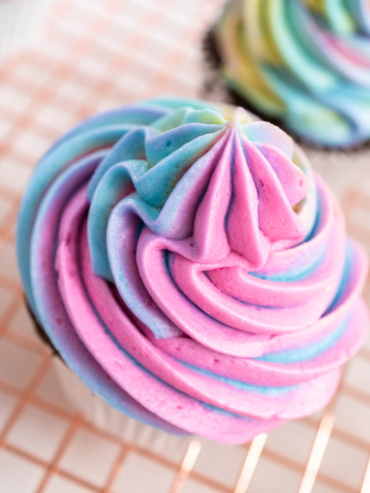 Nahaufnahme eines rosa-blauen Buttercreme-Wirbels auf einem Schokoladen-Cupcake