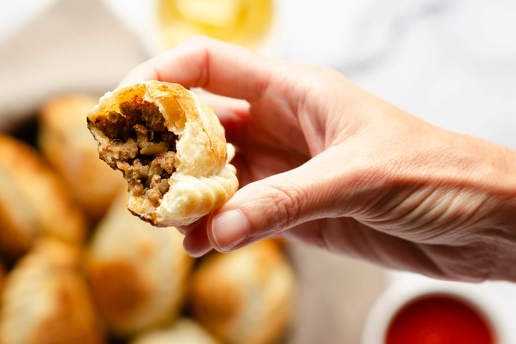 Aufgebrochene argentinische Rindfleisch-Empanada in einer Hand, die saftige Fleischfüllung ist sichtbar