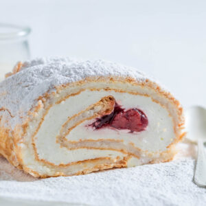 Angeschnittene Baiser-Roulade mit Sahne und Erdbeer-Füllung, Puderzucker bestäubt, mit sichtbarer Spirale