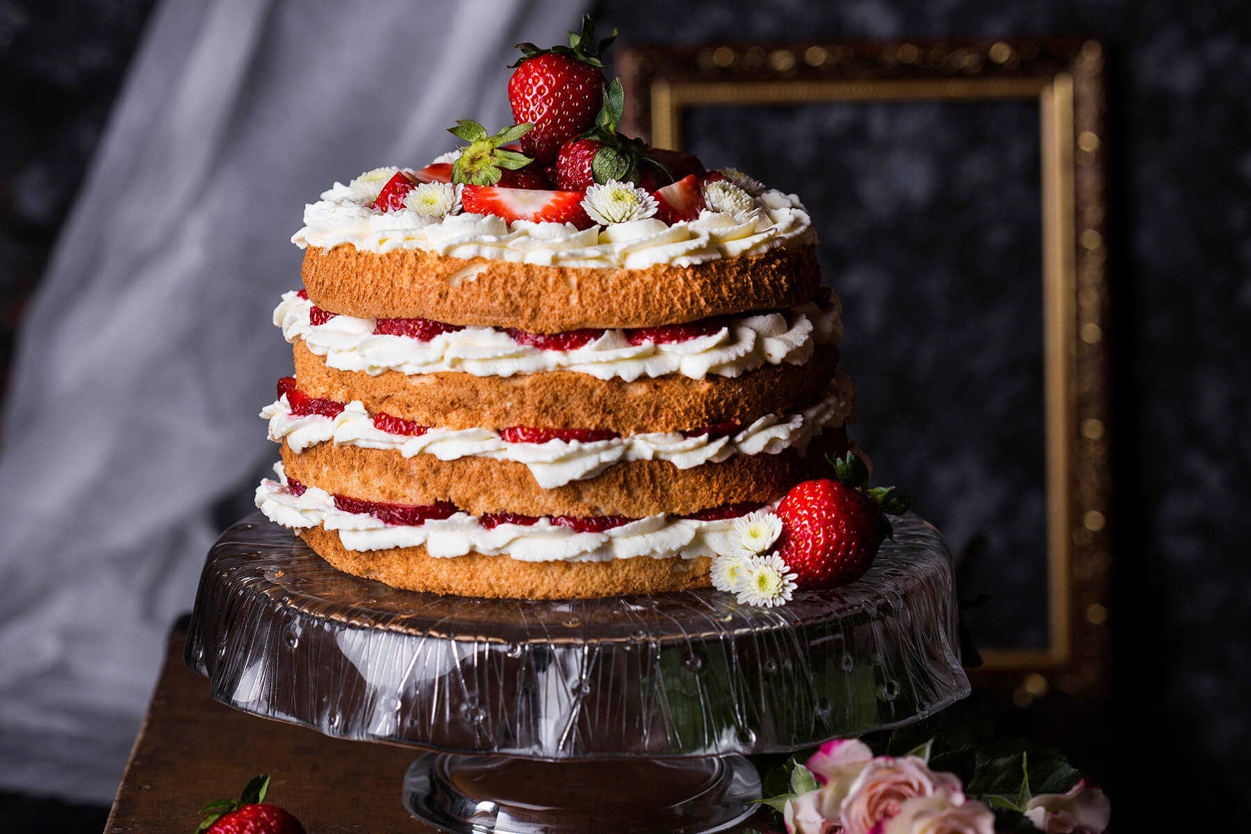 Seitenansicht der Erdbeer-Sahne-Torte mit mehreren luftigen Biskuitböden, dicken Sahneschichten und Erdbeeren zwischen den Lagen