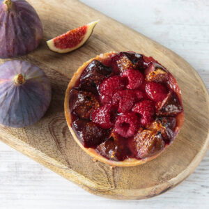 Feigen-Himbeer-Tartelette mit mitgebackenen Feigenspalten und Himbeeren, glänzend vom eingedickten Fruchtsaft, daneben frische Feigen