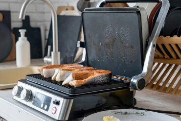 Goldbraun gegrillte Forellensteaks auf der offenen Grillplatte des Kontaktgrills