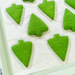 Grüne Lebkuchen-Tannenbäume nach dem Backen auf einem Blech in Nahaufnahme
