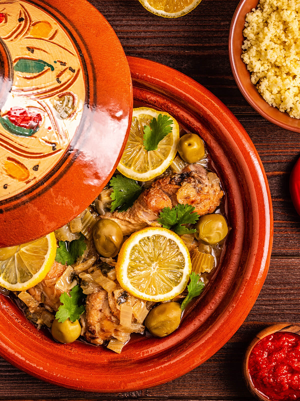 Marokkanische Hähnchen-Tajine mit grünen Oliven, Salzzitronen und Koriander in der Tajine, dazu Couscous und Harissa
