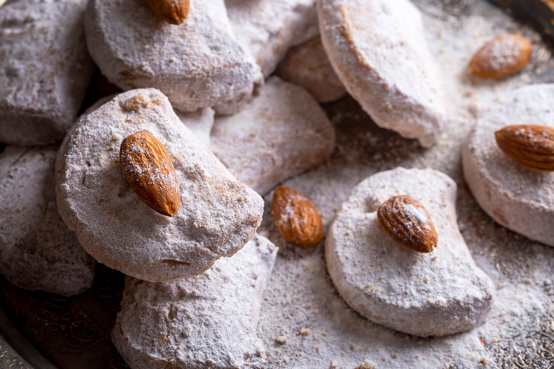 Nahaufnahme fertig gebackener Kavala Cookies mit ganzer Mandel, dick in weißem Puderzucker gewälzt