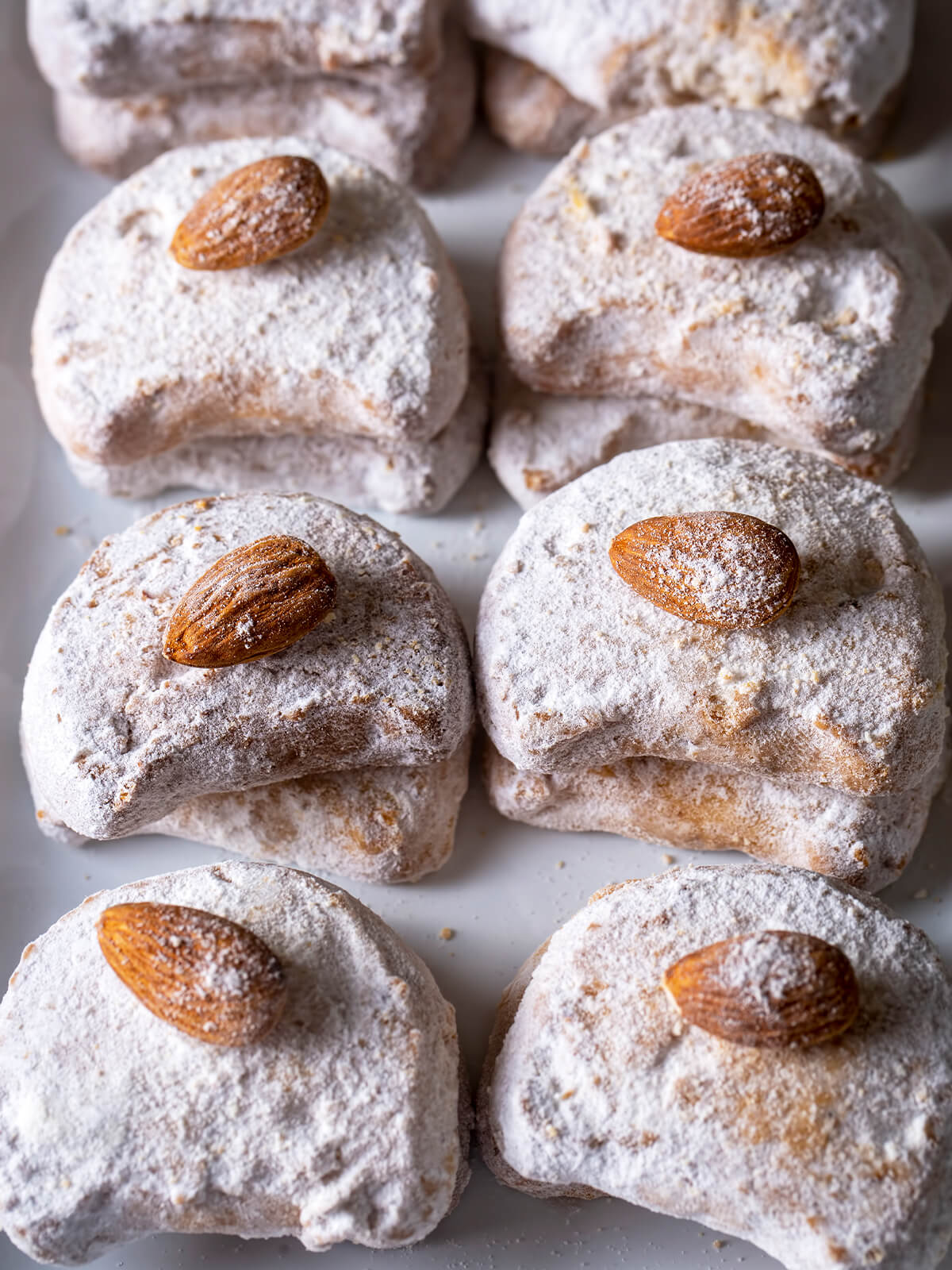 Ordentlich aufgereihte Kavala Cookies in Halbmondform, jeder mit ganzer Mandel und dicker Puderzuckerschicht, von oben fotografiert