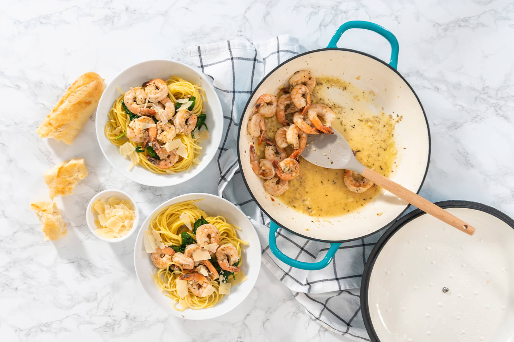Angerichtete Garnelen-Spaghetti-Teller neben der Pfanne mit Knoblauchbutter-Garnelen