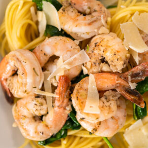 Gebratene Garnelen mit Spinat und Parmesanspänen auf Spaghetti in Nahaufnahme