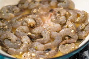 Rohe Garnelen mit gehacktem Knoblauch in geschmolzener Butter in der Pfanne
