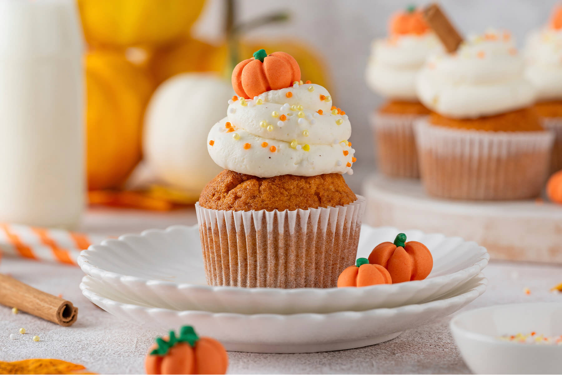 Kürbis-Cupcake in Nahaufnahme mit cremigem Frischkäse-Frosting und orangefarbenem Fondant-Kürbis obenauf
