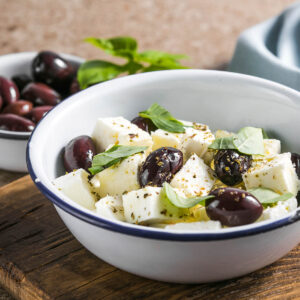 Marinierter Feta in Würfeln mit Kalamata-Oliven, Basilikum und Oregano in einer Emailleschale