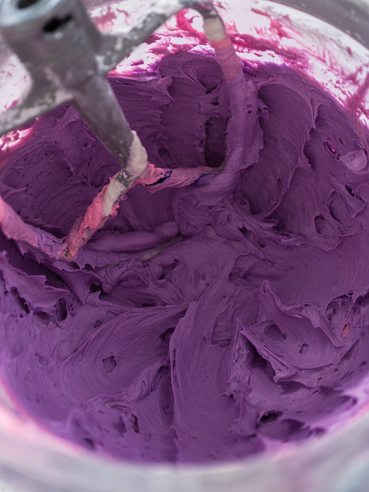 Eine Portion Buttercreme ist zu einem satten Violett eingefärbt und wird cremig gerührt
