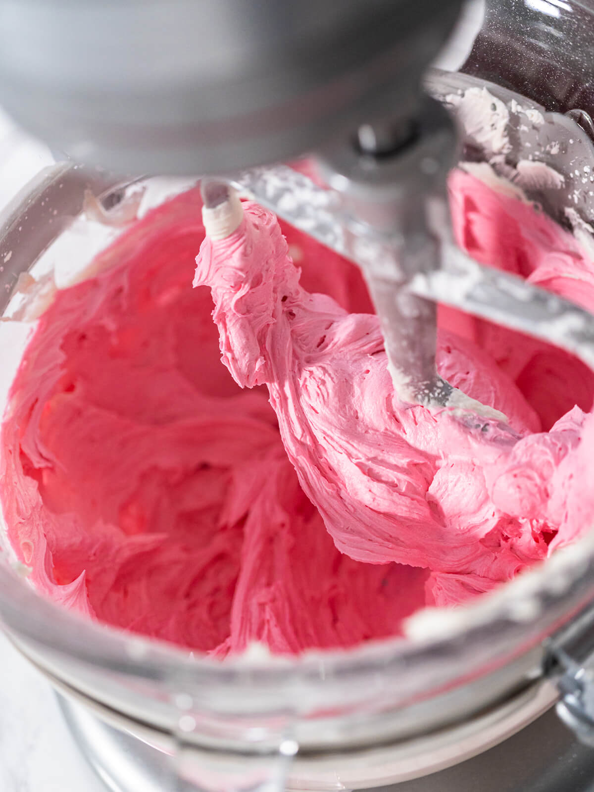 Eine Portion Buttercreme ist zu einem hellen Rosa eingefärbt und wird glatt gerührt