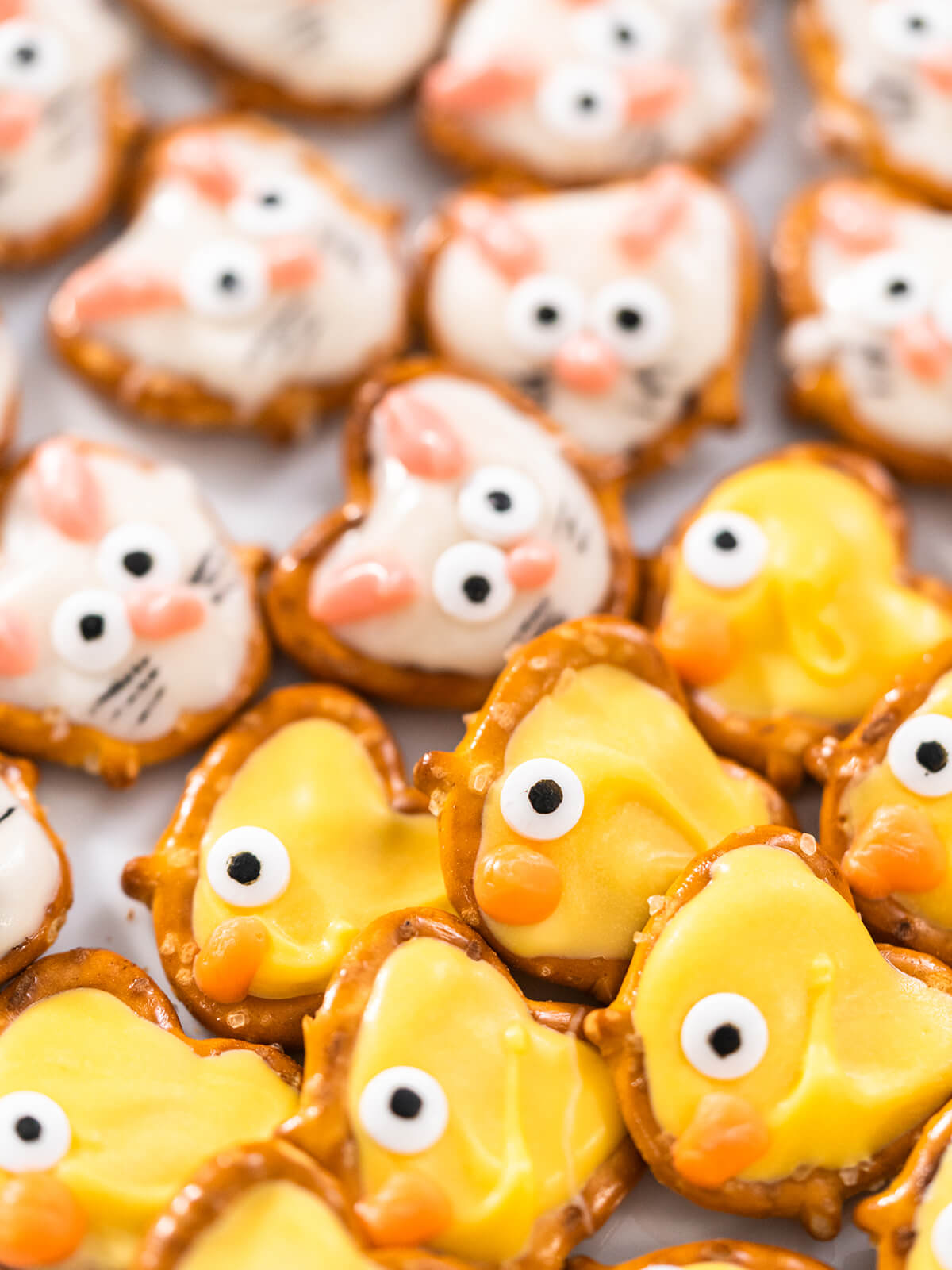 Oster-Schoko-Brezel als weiße Häschen mit rosa Öhrchen und gelbe Küken mit orangem Schnabel in Nahaufnahme