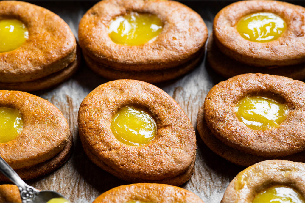Mehrere goldbraune Osterei-Plätzchen mit glänzendem Lemon Curd in der Mulde